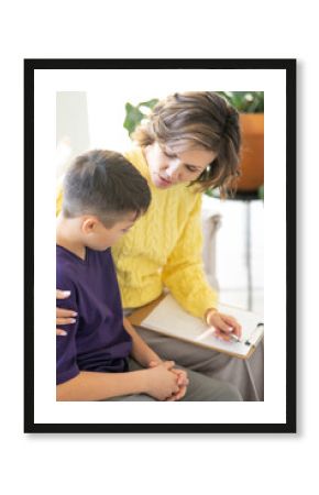 Close-up of teenager's eyelashes. Middle-aged woman psychologist accepts teenager in ight cozy office. Gives him support and care by holding his shoulder. Emotional intelligence. Vertical image.