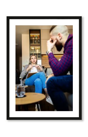 Young man talking to female psychologist during session.