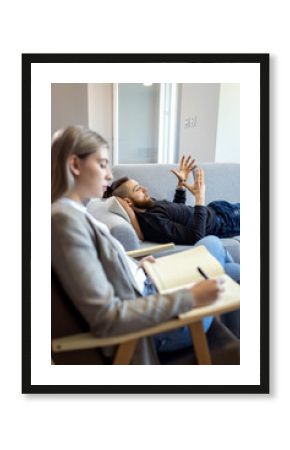 Young man talking to female psychologist during session.