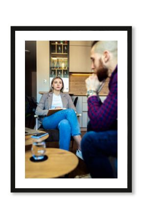 Female psychologist talking to young man during session.