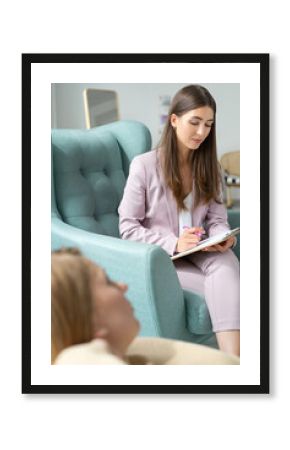 Middle-aged psychologist woman in a beautiful modern suit. Sitting in a comfortable chair for a consultation.