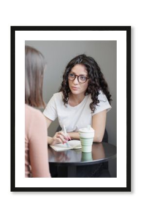 Spanish woman psychologist or business coach conducts a session with a client and takes notes in a notebook. formation, change of activity. Mental health and psychological health support