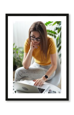 Young woman designer or freelancer working at home using computer sitting at table at home