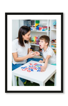 A cute boy with a speech therapist is taught to pronounce the letters, words and sounds.