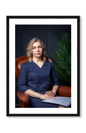 Portrait of a successful female psychologist in her office, notebook in hand, in her chair