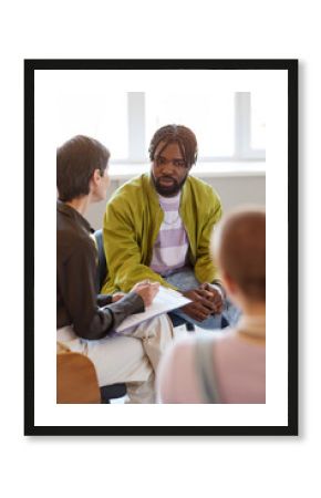 Vertical image of group of people talking to psychologist at session in the room