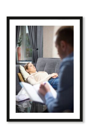 Male psychologist writes down stories about problems from girl and compiles client psychological profile. Sad teenager girl lies on couch sharing life stories