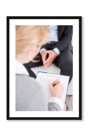 Female psychologist making notes during psychological therapy