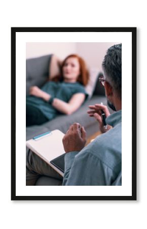 Psychotherapist with notes talking with client during therapy