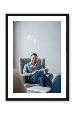 Handsome psychologist is making notes sitting in his office.