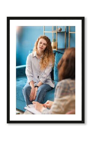 Unhappy red-haired woman talking to a female psychologist. Discusses her problems, mental trauma. Consultation in the office on the sofa.