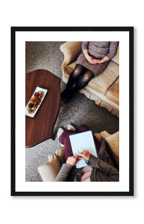 Professional psychologist doctor giving the consult to female patient. Close shot from above of two women during psychotherapy session. Therapist writing down notes during meeting with her patient