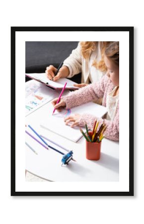  girl drawing pictures with colorful pencils while visiting psychologist