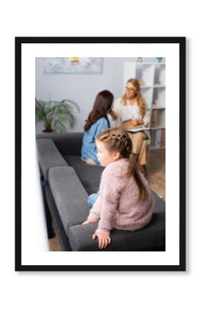 daughter sitting on sofa while mother talking to psychologist, stock image