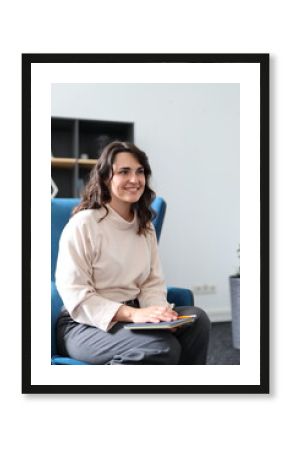 A woman is sitting in a chair with a book in her lap. She is smiling and she is enjoying her time