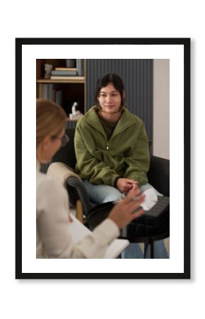 Vertical portrait of teenage girl listening to therapist in meeting and of troubled teenage girl sharing mental health problems