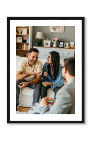 Young couple laughing and talking to psychologist during therapy session