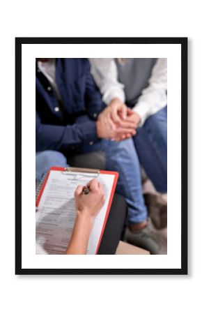 female psychologist listening to couple and making notes in document on clipboard, close-up. focus on paper and hand