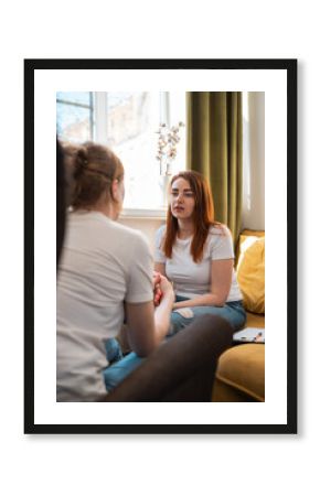 Young woman psychology therapist on yellow sofa with patient. Talking with empathy.