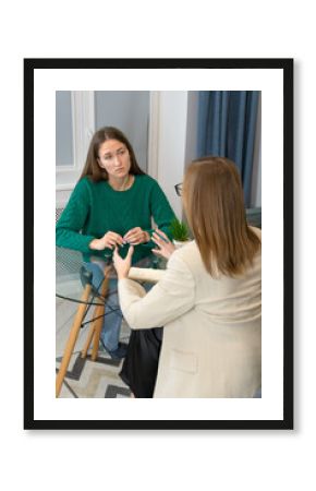 Young woman attentively and emotionally listens to a psychologist at the reception. Consultation of a psychologist in a modern office. Concept of psychological health. Vertical photo