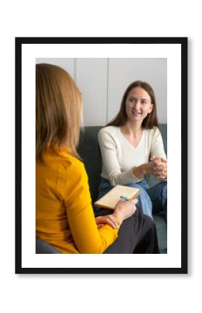 Smiling young woman listens to a psychologist at the reception, sitting on the couch in the office.Psychotherapist advises the patient about the results of the examination, gives recommendations