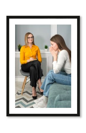 Counseling on depression, apathy. Young woman tells a psychologist about her life, she is sad, she put her hands to her face. Focus on the psychologist. Vertical photo