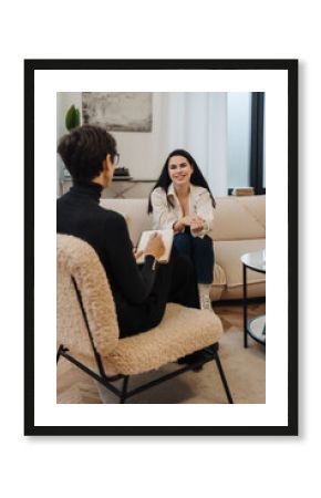 Psychologist writing down notes during therapy session with smiling woman