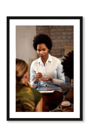 Female psychologist talking to group of diverse veterans during PTSD support group.