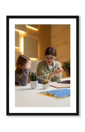 Child psychologist, additional classes with the child. The girl and her mother are doing the task at the desk.