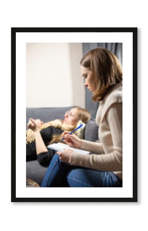 Female client answers questions about herself from specialist at psychologist appointment. Woman listens to answers and makes notes of important points
