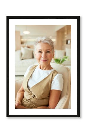 Portrait of elegant beautiful positive senior good-looking female HR sitting in armchair in cozy stylish bright lobby waiting for potential employee for interview on vacant position