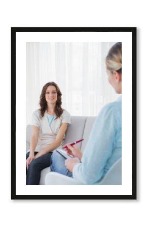 Brunette sitting on the couch while therapist is taking notes