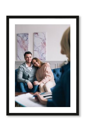 Beautiful young husband and wife are visiting a psychologist. Sitting and embracing.