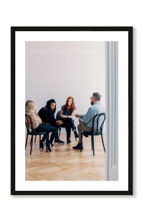 Group of rebellious teenagers talking to a psychologist in a rehab facility