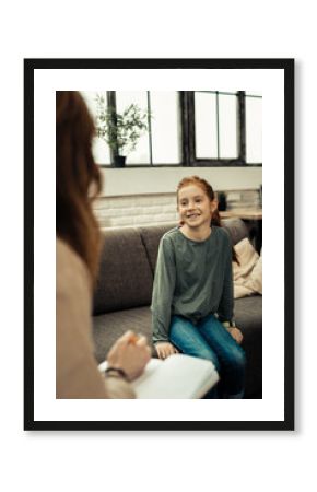 Joyful nice girl sitting on the sofa