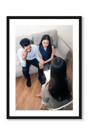 Asian woman consoling his husband sitting on couch With Psychologist..