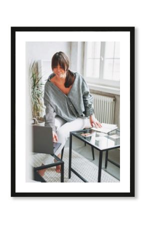 Working young brunette woman psychologist with laptop and associative cards near window at bright interior