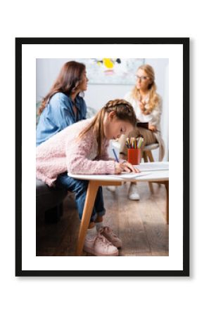 little girl patient drawing picture while visiting psychologist with mother, stock image
