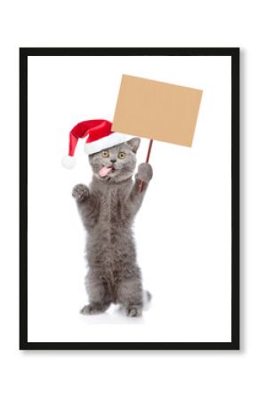 Surprised cat with tongue out wearing red christmas hat standing on hind legs and showing blank placard on wooden stick. Empty space for text. isolated on white background