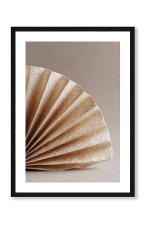 Minimalist still life highlighting texture and form. A folded paper element suggests preparation, filtering, or organic processes. Warm, neutral color palette.