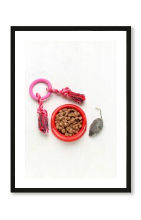 Bowl of wet pet food and toys on light background