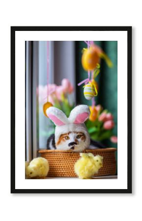 funny kitten lies in a basket on the windowsill among flowers and colorful Easter eggs