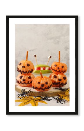 Scary monsters and ghosts made of apples and tangerines on old concrete background, cafe and menu advertising, restaurant business card, Halloween food concept, holiday meal idea for kids and adults.