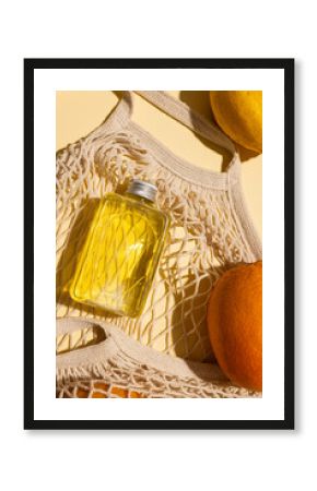 Close up of beauty product bottles, oranges and net bag with copy space on yellow background