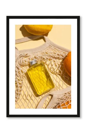 Close up of beauty product bottles, oranges and net bag with copy space on yellow background