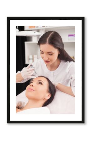 Cheerful female expert beautician is serving her patient