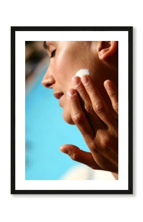 femme à la piscine s'appliquant de la crème solaire