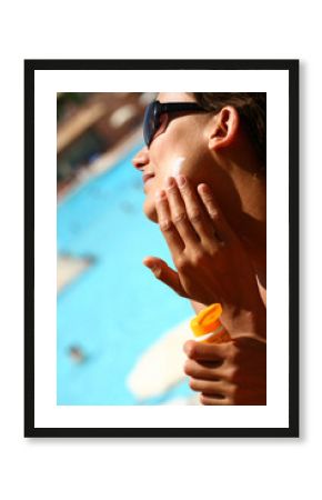 femme à la piscine appliquant une crème solaire sur le visage