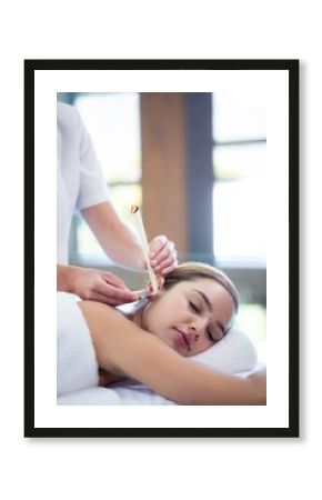 Woman receiving ear candle treatment