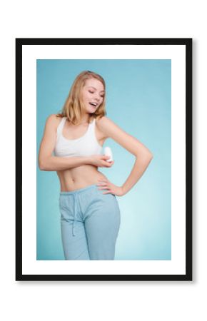 Girl applying stick deodorant in armpit.